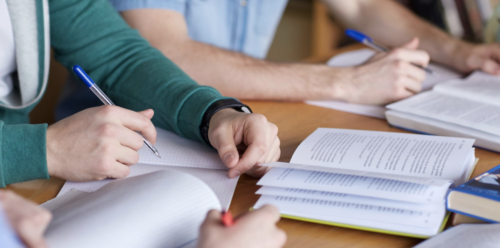 hands at a table in front of a book