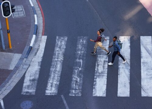 Two young pedestrians cross the road on a crosswalk in the city
