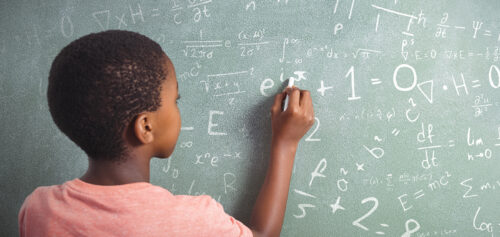 A student solves math problems on a blackboard.