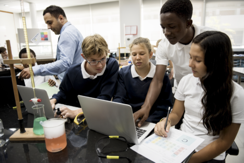 kids in science classroom gathered together around a computer