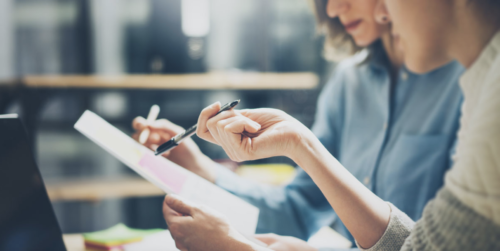 two adults pointing at a piece of paper