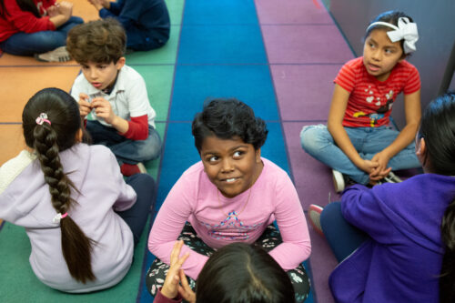 Kids on classroom carpet smiling