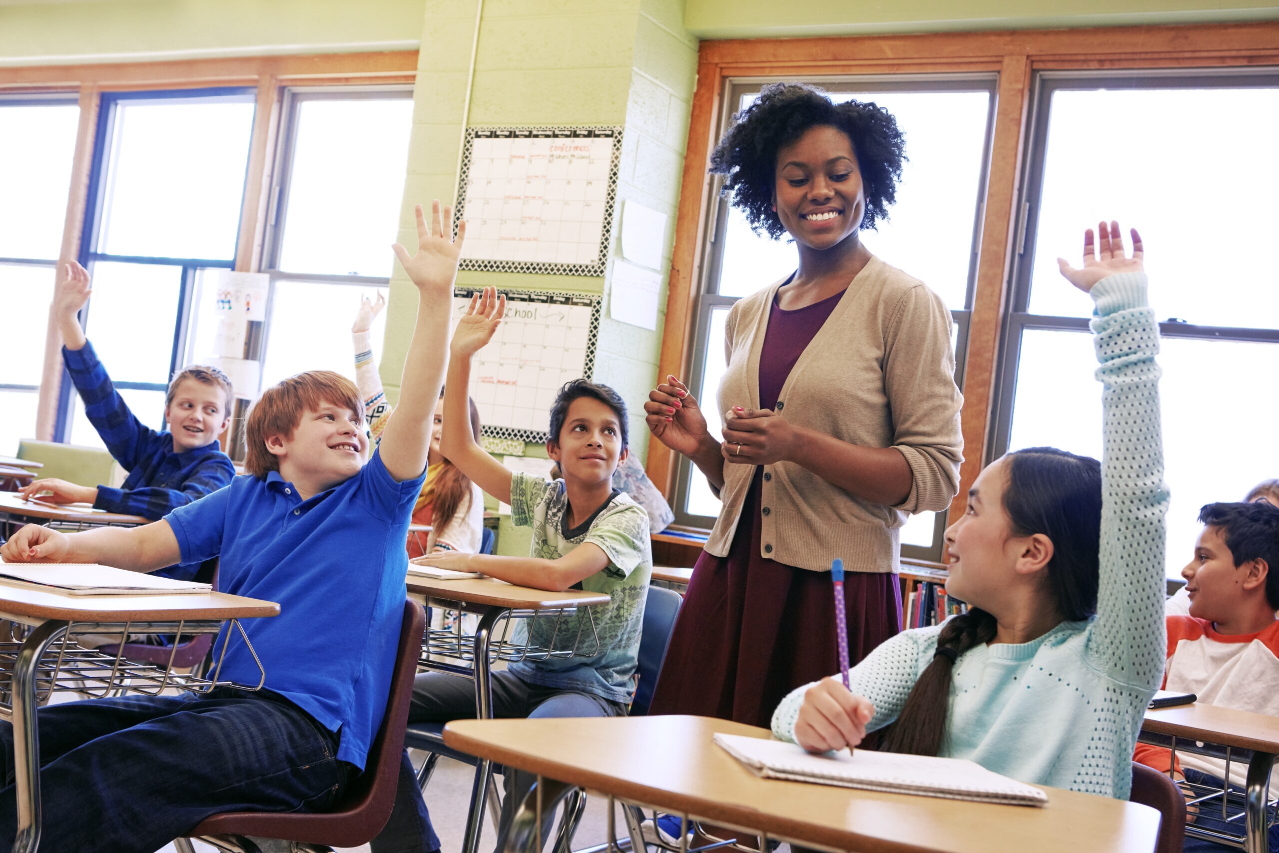Teacher standing in rows of students with hands raised