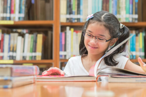 young girl reading a book in library